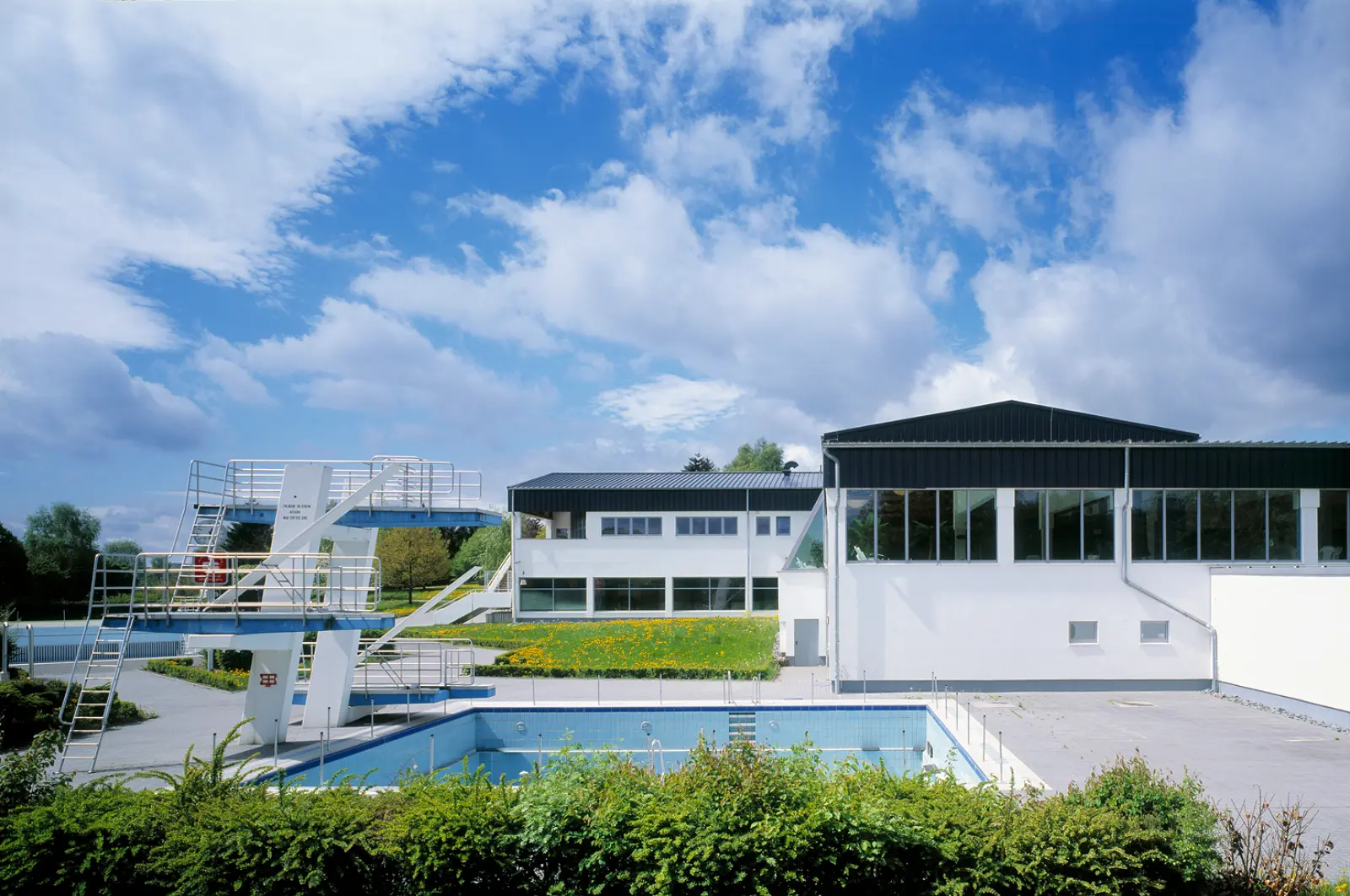Außenbecken des Rothaarbads mit Sprungturm und modernem Schwimmbadgebäude im Hintergrund.