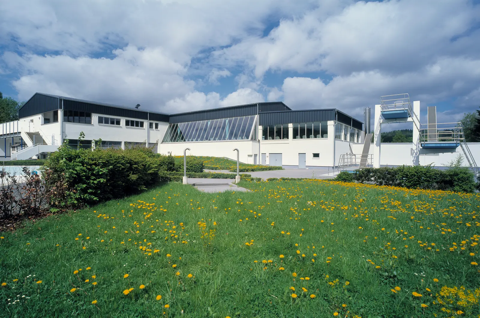 Rothaarbad mit modernem Schwimmbadgebäude, Außenbecken, Sprungturm und großzügigen Grünflächen.