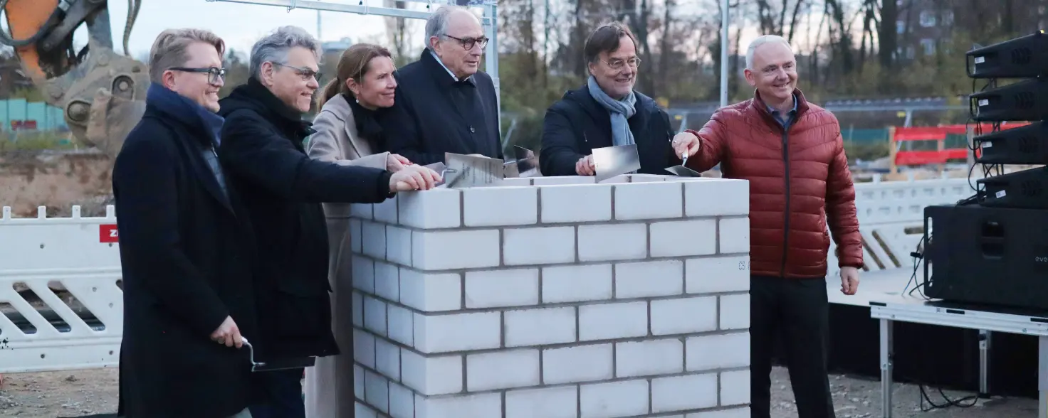 Neubauprojekt Marienhöfe in Berlin: Projektbeteiligte mit Maurerkellen lehnen an einem weißem gemauerten Schacht.