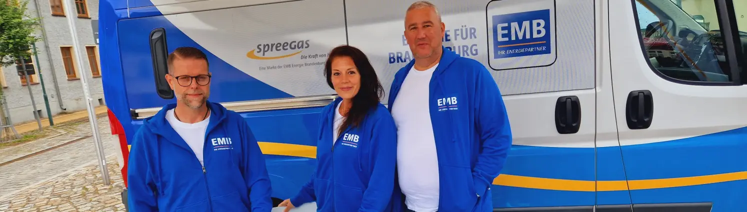 Drei Vertreter der EMB stehen vor einem Firmenwagen