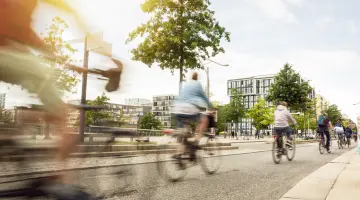 Menschen fahren auf Fahrrädern durch eine moderne Stadt mit viel Grün