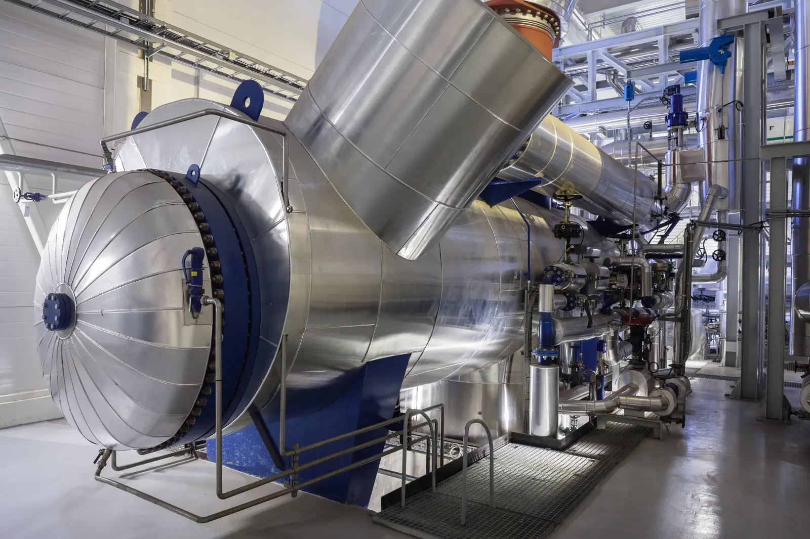 Ein großes, silbernes Blockheizkraftwerk steht in einem Heizkeller