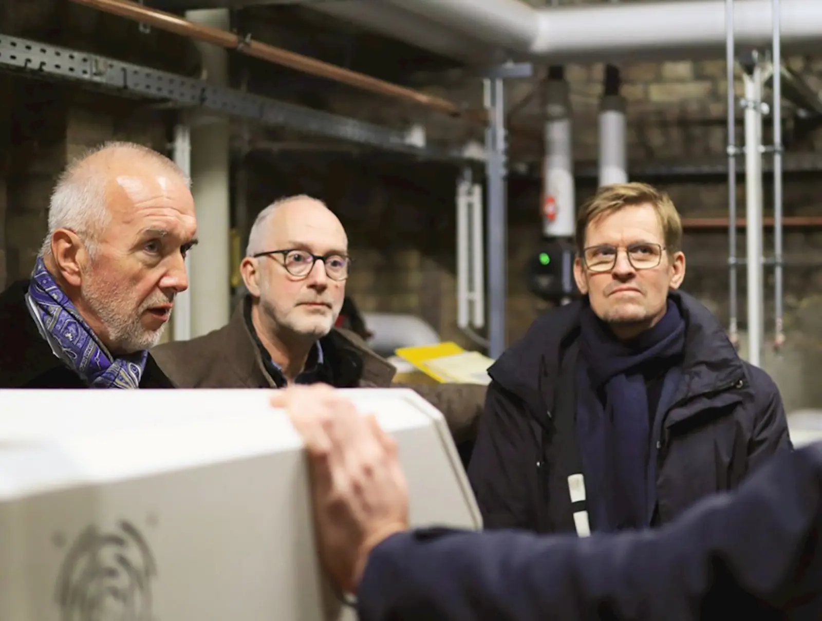 Mehrere Projektbeteiligte besichtigen die Energiezentrale der Apostel-Paulus-Kirche und informieren sich über die Wärmeversorgung. Bild mit KI erstellt.