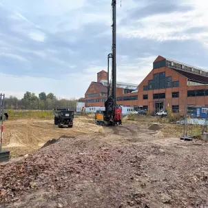 Geothermie-Bohrung vor zwei historischen Industriehallen auf der Baustelle des neuen Stadtquartiers Gartenfeld in Berlin-Spandau. Bild mit KI erstellt.
