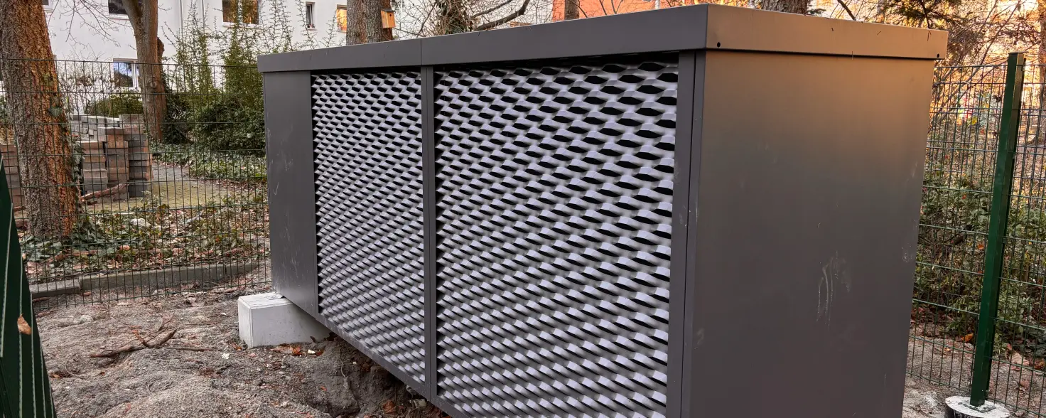 Projekt Winterfeldstraße der GASAG Solution Plus: Eine Wärmepumpe in einer dunkelgrauen Metalleinhausung steht auf zwei Betonblöcken verankert.